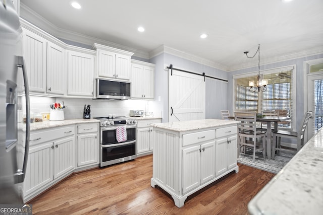 kitchen with white cabinetry, stainless steel appliances, a barn door, and pendant lighting