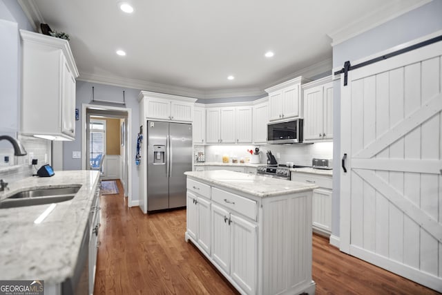 kitchen with white cabinetry, stainless steel appliances, a barn door, and a center island