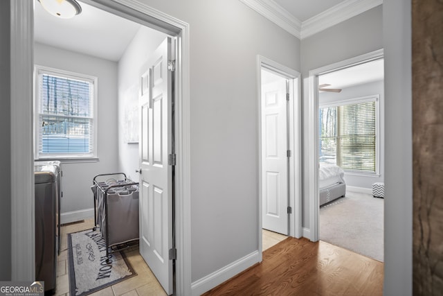 corridor featuring washer / dryer, ornamental molding, and light hardwood / wood-style floors