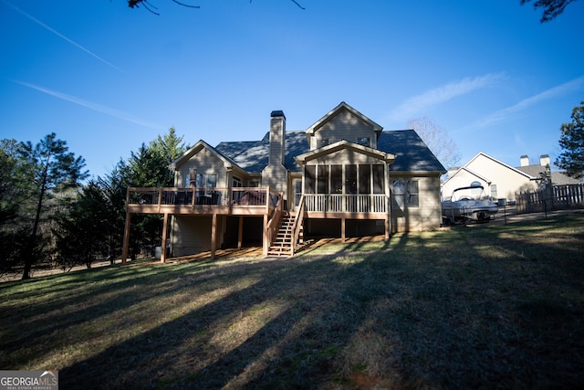 back of property with a lawn, a sunroom, and a deck