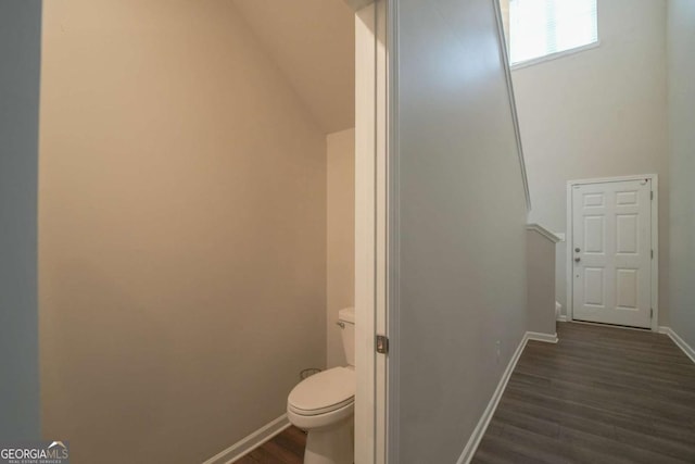 bathroom with toilet, lofted ceiling, and wood-type flooring