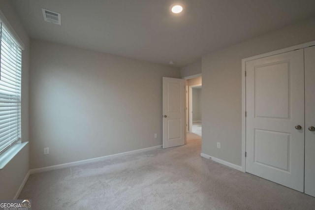 unfurnished bedroom with a closet and light colored carpet