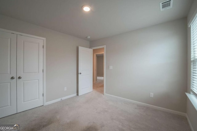 unfurnished bedroom with a closet and light carpet