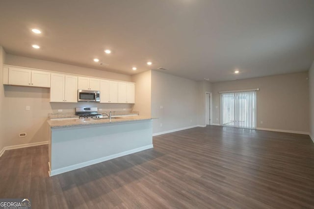 kitchen with dark wood-type flooring, white cabinets, light stone countertops, and stainless steel appliances