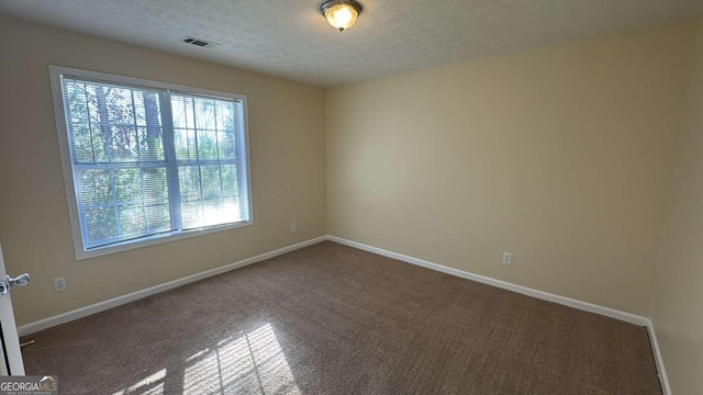 carpeted empty room featuring a textured ceiling