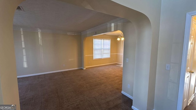 empty room with crown molding, dark carpet, and a notable chandelier