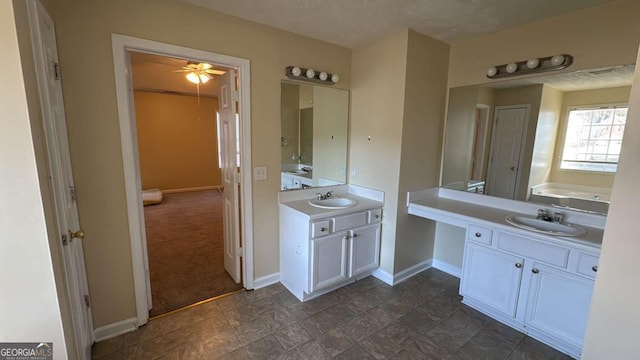 bathroom with ceiling fan, a textured ceiling, a bathtub, and vanity