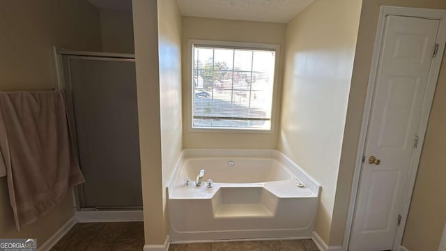 bathroom with a textured ceiling and separate shower and tub