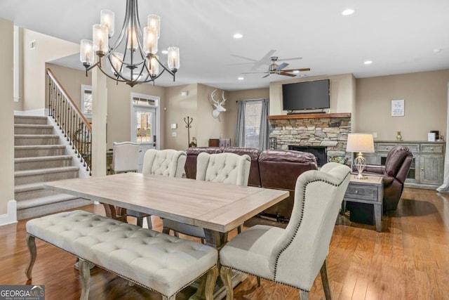 dining room featuring ceiling fan with notable chandelier, light hardwood / wood-style floors, and a fireplace