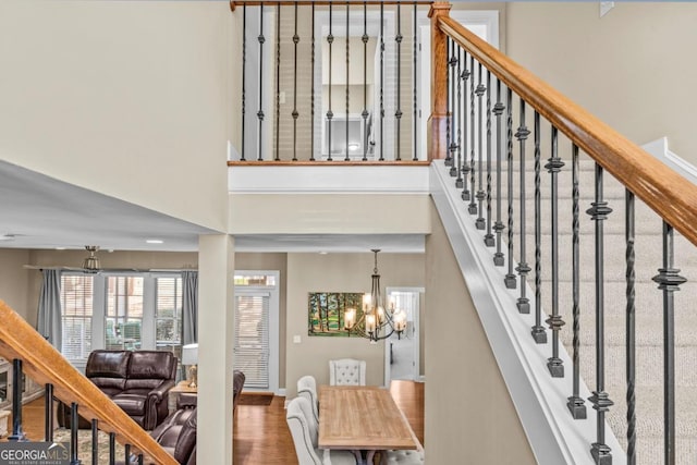 stairs featuring wood-type flooring and a chandelier