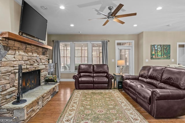 living room featuring ceiling fan, a fireplace, and wood-type flooring