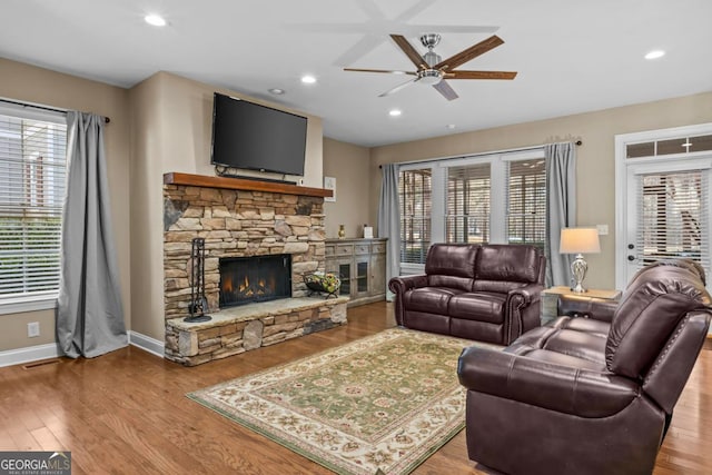 living room with ceiling fan, a fireplace, and wood-type flooring