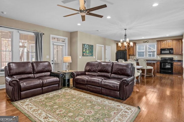 living room with dark wood-type flooring and ceiling fan with notable chandelier