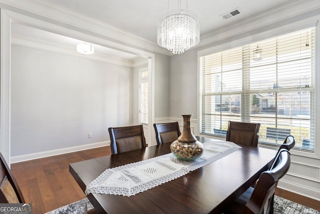 dining room with dark wood-type flooring, ornamental molding, and a chandelier