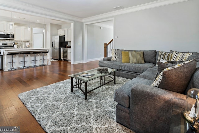 living room featuring dark hardwood / wood-style flooring, wine cooler, ornamental molding, and sink