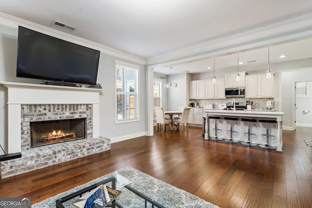 living room with a brick fireplace, dark hardwood / wood-style floors, and ornamental molding