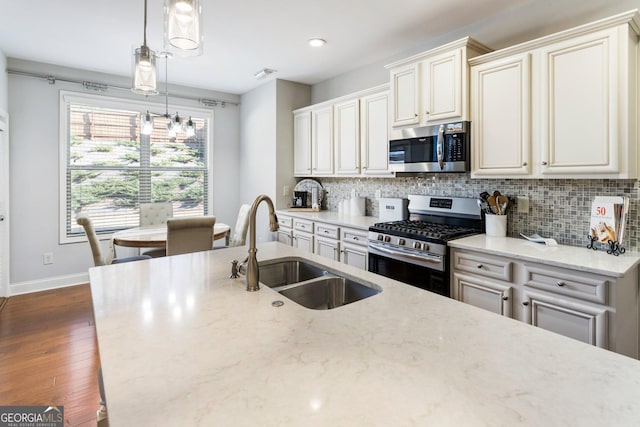 kitchen with sink, hanging light fixtures, appliances with stainless steel finishes, dark hardwood / wood-style flooring, and light stone counters