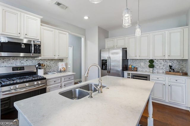 kitchen featuring appliances with stainless steel finishes, a kitchen island with sink, white cabinetry, and sink