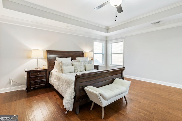 bedroom with ceiling fan, ornamental molding, a raised ceiling, and dark hardwood / wood-style floors