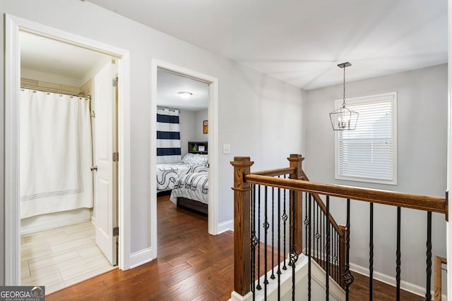 hallway with dark hardwood / wood-style flooring and a chandelier