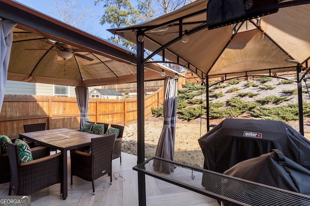 wooden terrace featuring ceiling fan, a gazebo, and grilling area