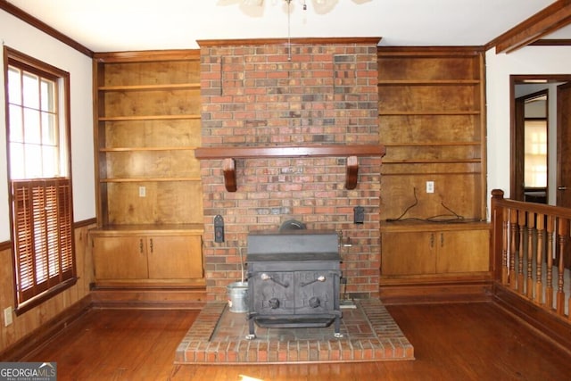 unfurnished living room with a wood stove, wooden walls, ornamental molding, and wood finished floors