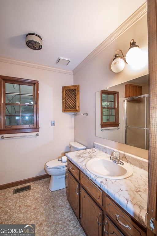 full bathroom featuring a stall shower, visible vents, toilet, crown molding, and vanity