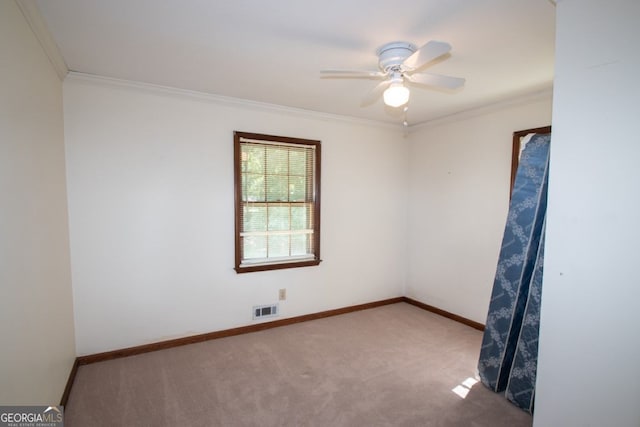 empty room with baseboards, visible vents, carpet flooring, and ornamental molding