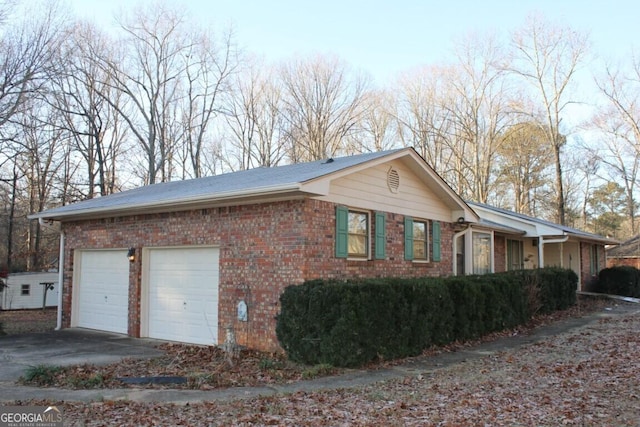 view of home's exterior with a garage, concrete driveway, and brick siding