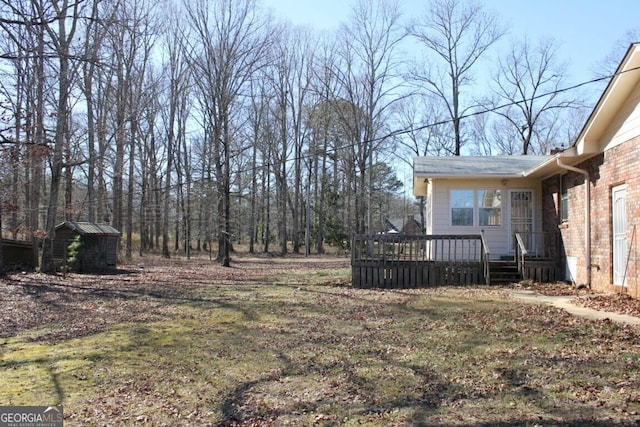 view of yard with a wooden deck, a storage unit, and an outbuilding