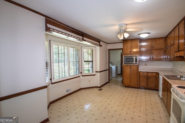 kitchen with white appliances, washer / clothes dryer, light floors, and a sink