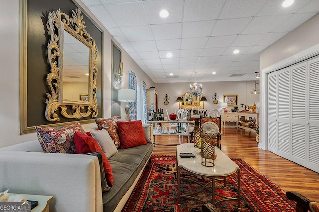 living room with a chandelier, a drop ceiling, and hardwood / wood-style floors