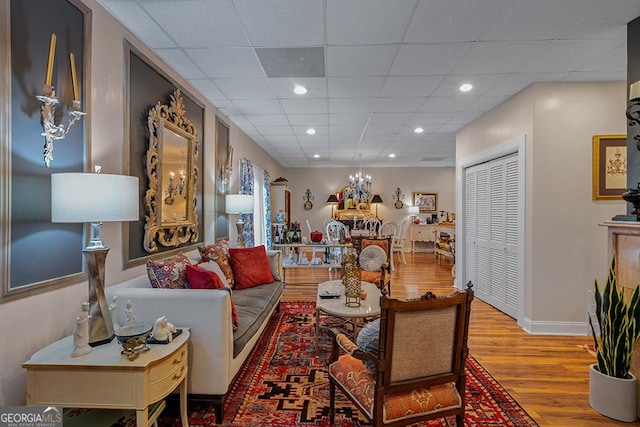 living room with light wood-type flooring and a paneled ceiling