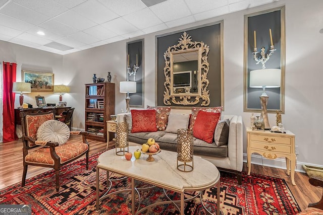 living room with a drop ceiling and wood-type flooring