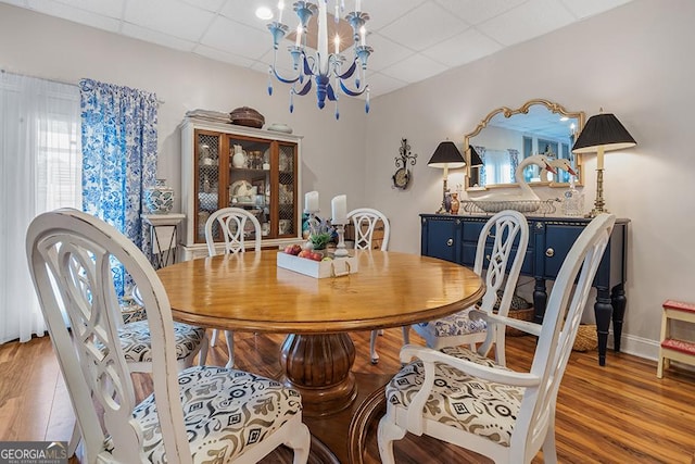 dining room featuring light wood-type flooring, a paneled ceiling, and a notable chandelier