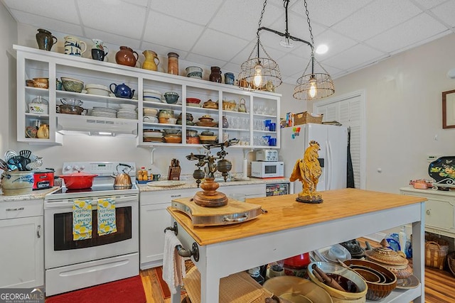 kitchen with white cabinetry, decorative light fixtures, white appliances, a paneled ceiling, and light stone countertops