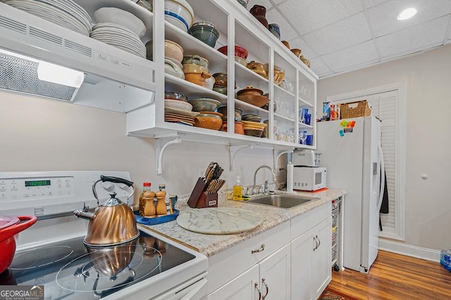 kitchen with extractor fan, sink, white appliances, white cabinets, and light stone counters