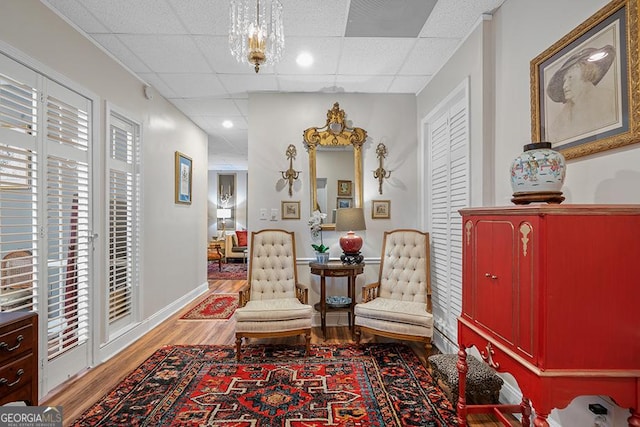 sitting room featuring a paneled ceiling, a notable chandelier, and hardwood / wood-style flooring