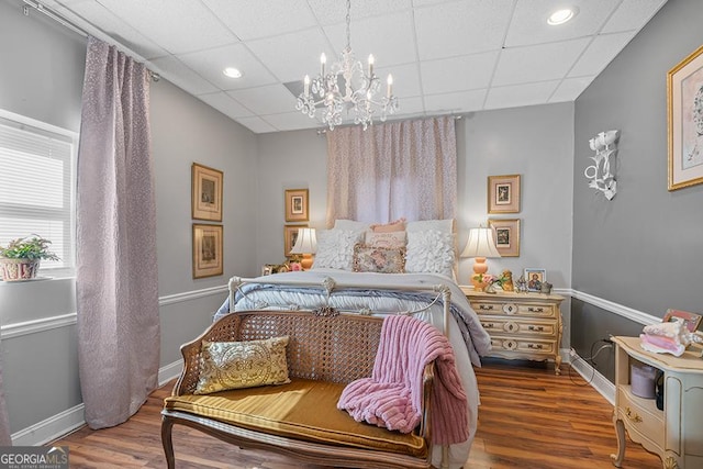 bedroom featuring a paneled ceiling, a notable chandelier, and hardwood / wood-style flooring