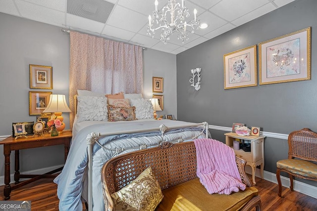 bedroom featuring a paneled ceiling, an inviting chandelier, and hardwood / wood-style floors