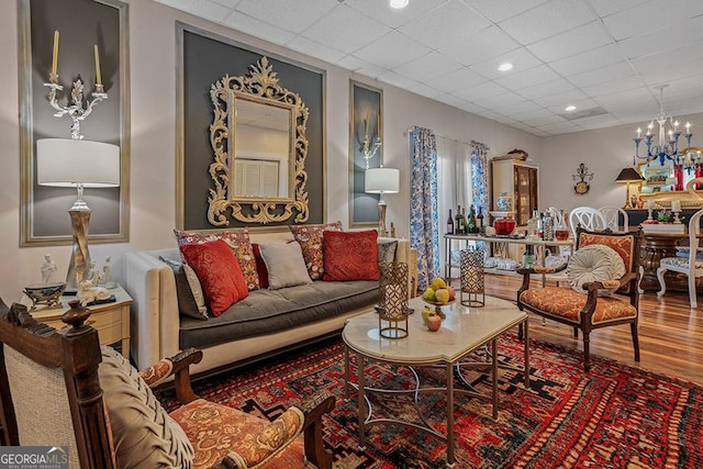 living room with a paneled ceiling, hardwood / wood-style floors, and a notable chandelier