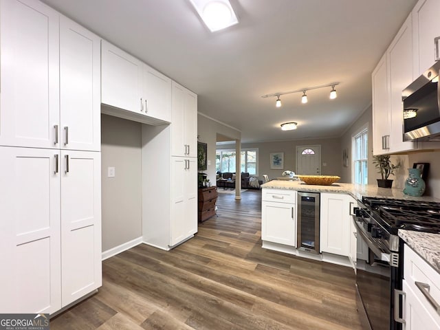 kitchen featuring wine cooler, a peninsula, gas range, and white cabinetry