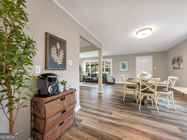 dining area featuring baseboards, wood finished floors, and crown molding
