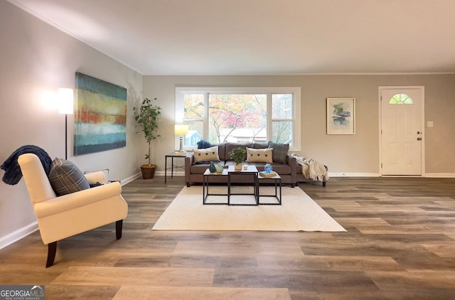 living room with crown molding, baseboards, and wood finished floors