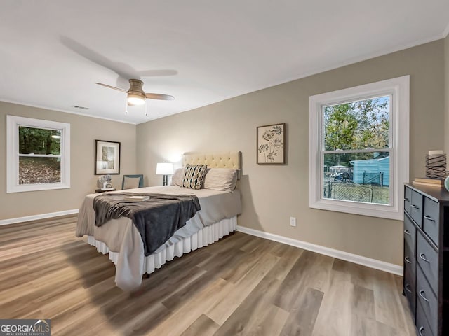bedroom with visible vents, baseboards, wood finished floors, and a ceiling fan