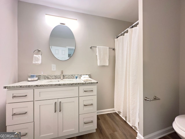full bath with baseboards, toilet, wood finished floors, and vanity