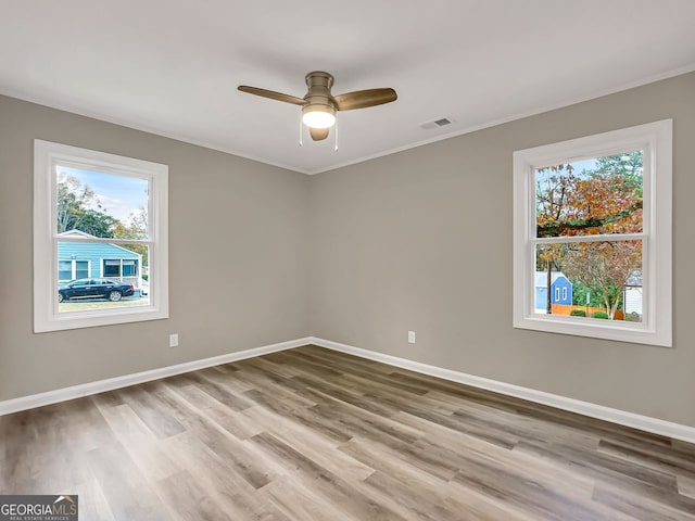 spare room with ceiling fan, baseboards, wood finished floors, and ornamental molding