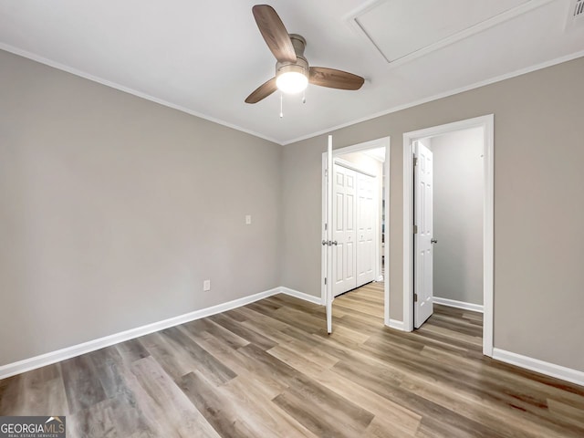 unfurnished bedroom featuring a ceiling fan, wood finished floors, baseboards, and ornamental molding