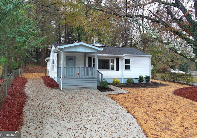 view of front facade with crawl space, covered porch, roof with shingles, and fence