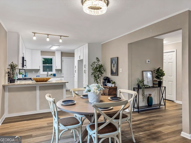 dining room with an inviting chandelier, wood finished floors, baseboards, and ornamental molding